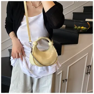 Detail of creamy yellow mini dumpling bag with knotted handle on a fashion model