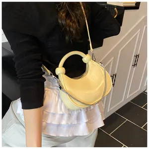 Detail of light yellow mini dumpling bag with unique circular handle and metal chain strap