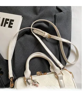 Detail of off-white woven texture handbag with adjustable strap on a grey blazer