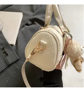Detail of woven beige Boston bag with gold hardware and plush bear charm decoration