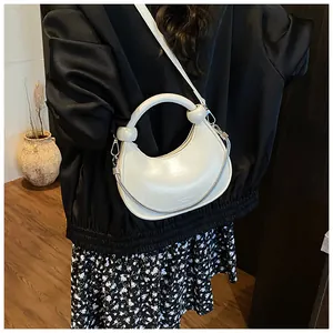Detail view of cream white half-moon crossbody bag with silver chain and thin strap