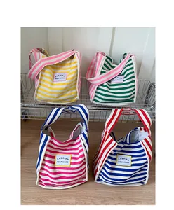 Detail view of colorful striped canvas tote bags in yellow, green, pink, and blue colorways
