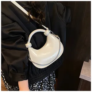Detail of white mini crescent bag with glossy finish and knotted circular handle with chain