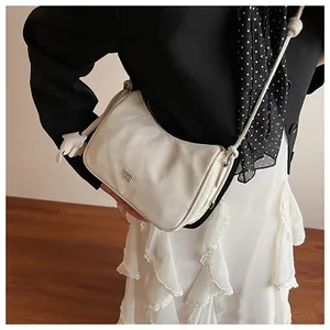 Detailed view of a white half-moon crossbody bag with textured leather and silver logo