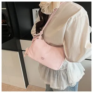 Detailed view of pink pleated hobo bag with metal logo and slender shoulder strap