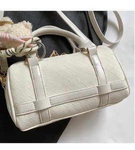 Detail of beige woven cylinder handbag showing intricate texture and golden hardware