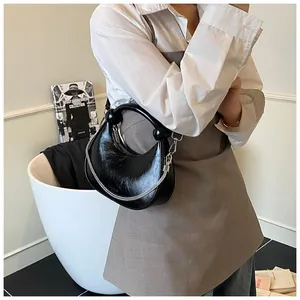 Detail of black glossy wrinkled patent leather handbag with silver chain and handle