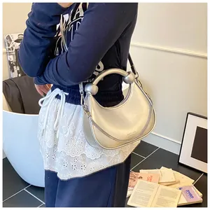 Detail of silver metallic hobo bag featuring a round metal handle and chain strap