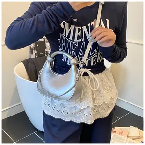 Silver crescent bag with knotted handle and chain detail shown on a fashion model