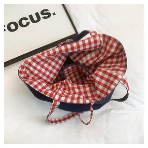 Detail view of denim tote bag with red and white plaid lining and interior pocket