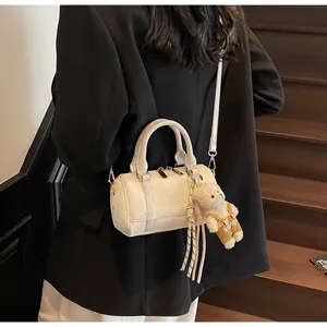Detail of off-white woven texture boston bag with cute teddy bear charm accessory