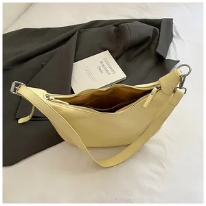 Detail of light yellow crocodile-textured faux leather bag with silver metal buckle strap