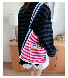 Close-up of pink striped canvas tote bag with yellow brand label and contrast strap