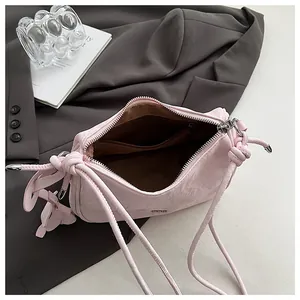 Detail view of pink pleated handbag with interior lining, zipper pocket and flower charm