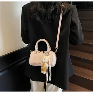 Detail of light pink cylindrical crossbody bag with woven texture and cute bear charm