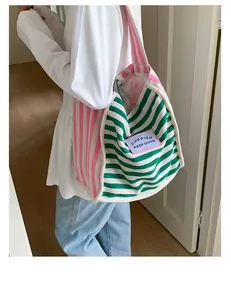 Detail of canvas tote bag featuring pink and green stripes with a logo patch