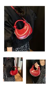 Detail view of red crescent handbag with round handle and silver chain strap