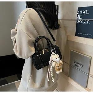 Detail of black leather Boston bag with gold hardware and white bear charm accessory
