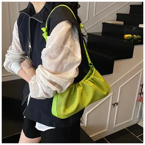 Detail of neon green pleated shoulder bag with textured fabric and knotted strap