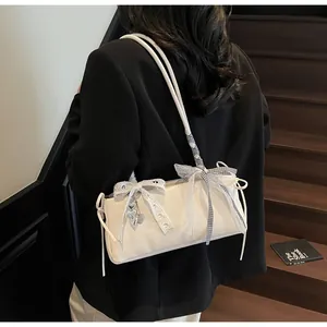 Detail der weißen Achseltasche mit Spitzenschleife, Karoband und Herzanhänger