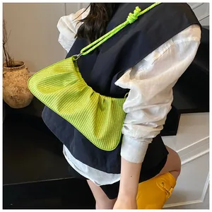 Detail of neon green pleated shoulder bag with knotted strap on minimalist black outfit