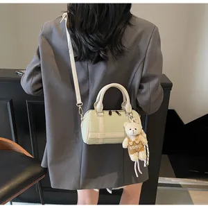 Detail of mint green Boston bag with plaid texture and cute bear pendant on a model