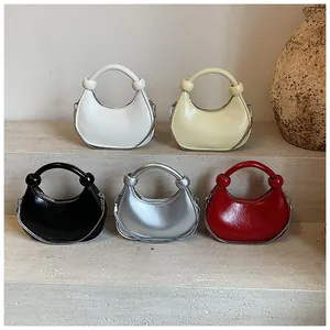 Detail view of mini crescent bags in white, yellow, black, silver and red with chain decor