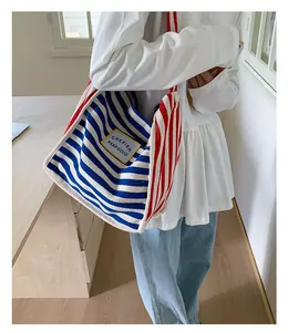 Detail of colorful striped canvas tote bag with yellow patch showing side view on model