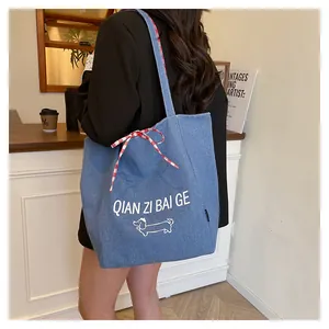 Detail of blue denim tote bag with red gingham bow and cute puppy graphic on the fabric