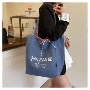 Detail of large denim tote bag with dog graphic and red gingham inner lining