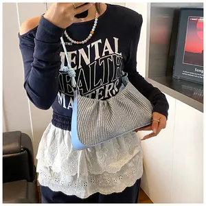 Blue houndstooth pleated baguette bag with leather strap knot detail shown on model