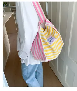 Detailed macro view of vibrant yellow and pink striped canvas tote bag with woven label