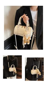 Detail of off-white cylindrical bag showing woven texture and cute plush bear pendant