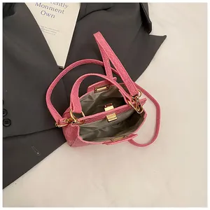 Sac à main rose avec motif crocodile, poignée dorée et bandoulière amovible