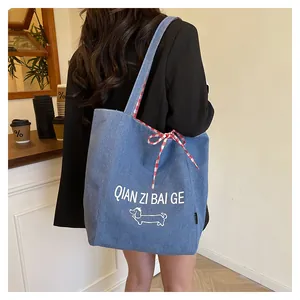 Close-up of blue denim tote bag with cartoon dog print and red plaid bow detail