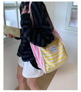 Detail view of large striped canvas shoulder bag worn by model in a natural light setting