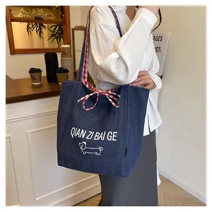 Detail of blue denim tote bag featuring red checkered lining and a cute dog print
