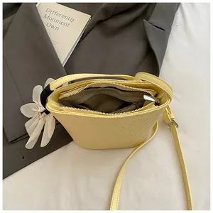 Sac seau tissé jaune pâle à la mode avec pendentif fleur sur fond de costume gris