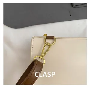 Detail van de gouden musketonhulp en bruine leren riem op de crème-kleurige tas