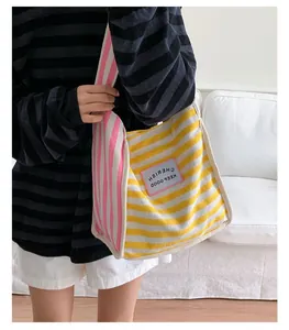 Close-up of contrast striped canvas tote bag with KEEP GOOD CHERISH patch detail