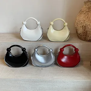 Minimalist summer dumpling crossbody bags in five colors with knot handles on stone steps