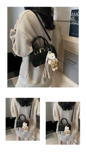 Detail of black mini Boston handbag with golden hardware and cute bear pendant