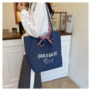 Detail of blue denim tote bag with dog print, checkered lining, and bow tie closure