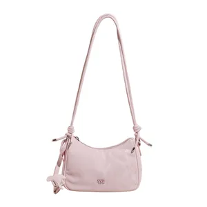 Light pink half-moon shoulder bag with knot strap and elephant charm on white background