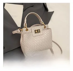 Détail du sac tressé crème avec fermoir rotatif en métal doré et texture raffinée