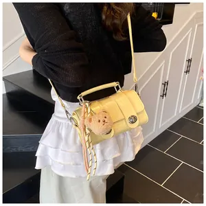 Detail of light yellow crocodile texture bag with bear charm and silver twist lock