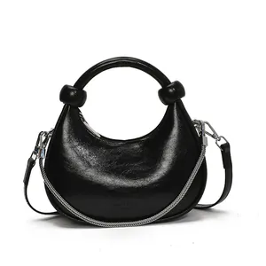 Glossy black croissant handbag with silver chain and adjustable shoulder strap