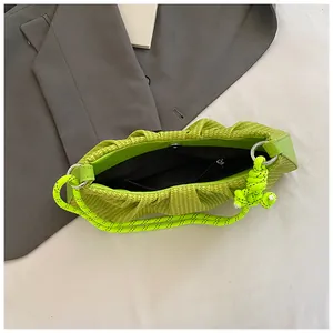 Neon green pleated cloud bag with knotted strap on a grey blazer, stylish underarm bag