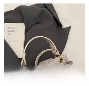 Détail de la texture tressée du sac en similicuir avec anneau doré et poignée