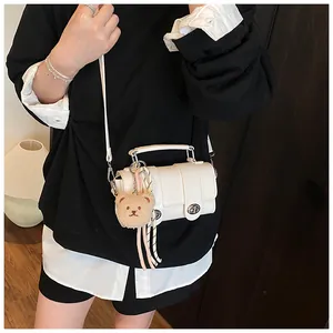 Detail of white crocodile embossed mini bag with silver lock and plush bear charm